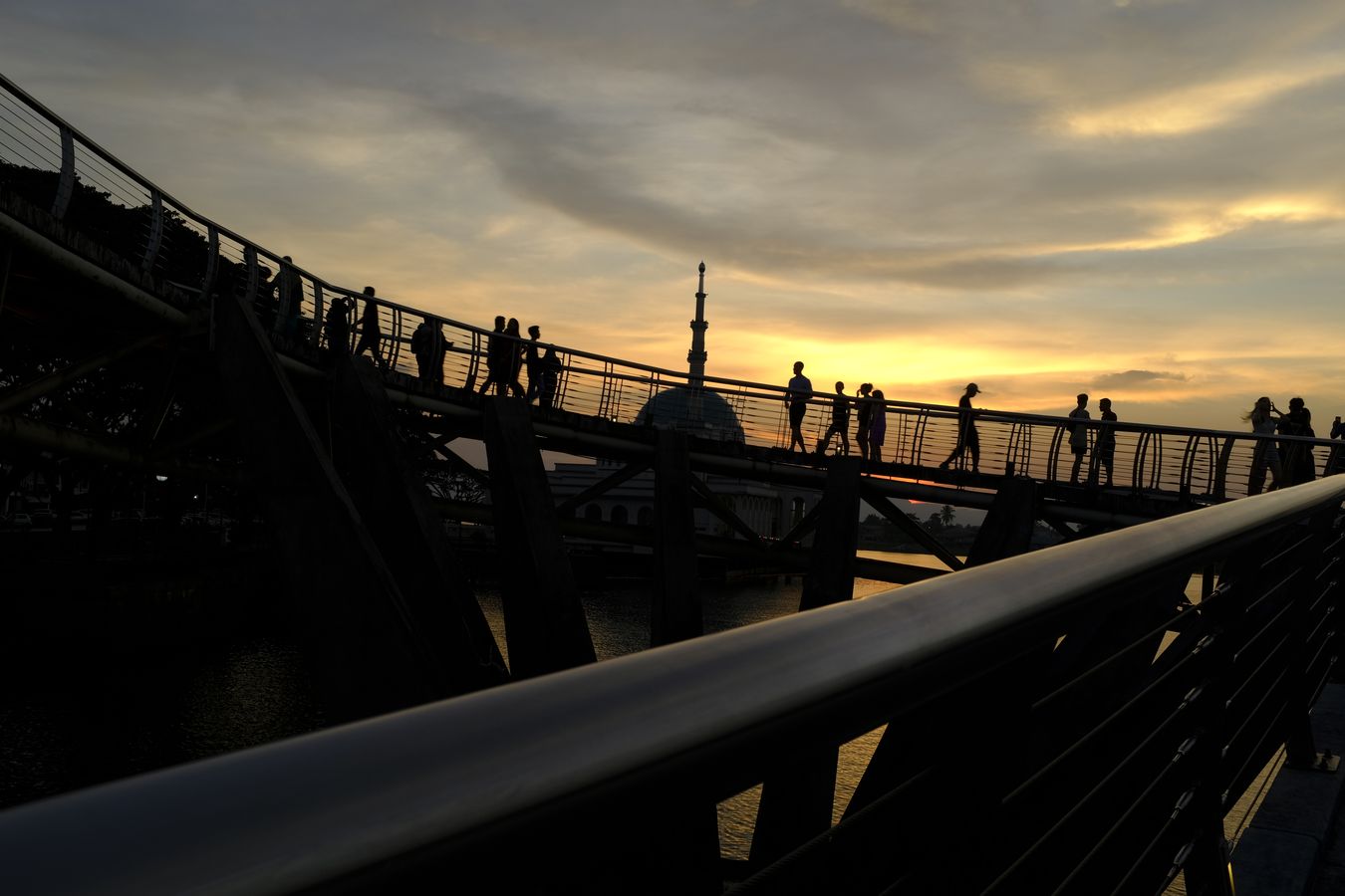 Partial view of the Darul Hana bridge at sunset with the minaret of the floating mosque behind