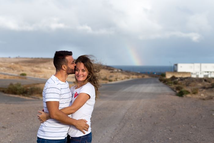 Novios abrazados al atardecer con arcoíris al fondo
